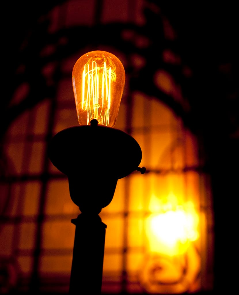A glowing filament bulb against a dark window