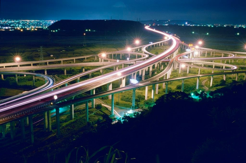Light trails sweeping across a motorway interchange at night