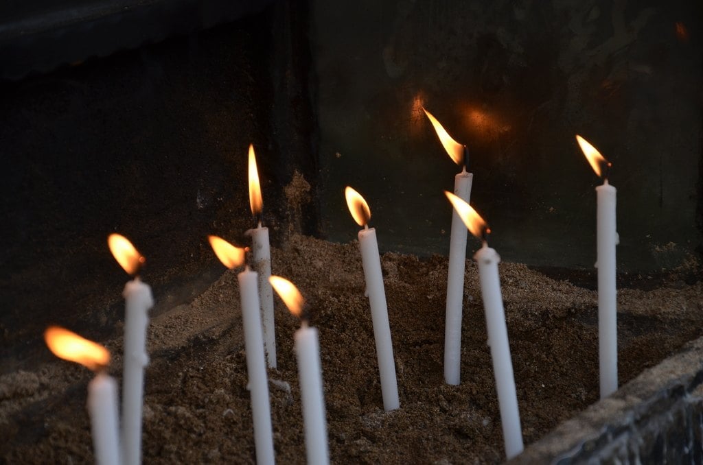 Rows of thin candles burning in sand