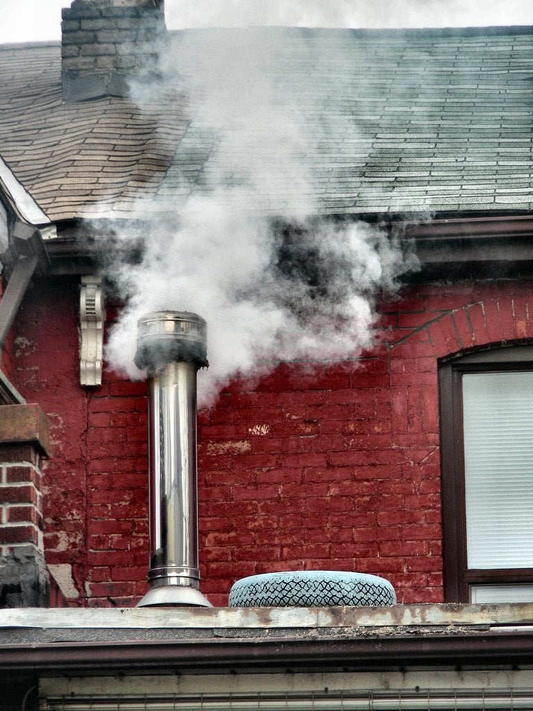 Steam rising from a chimney on a red brick roof