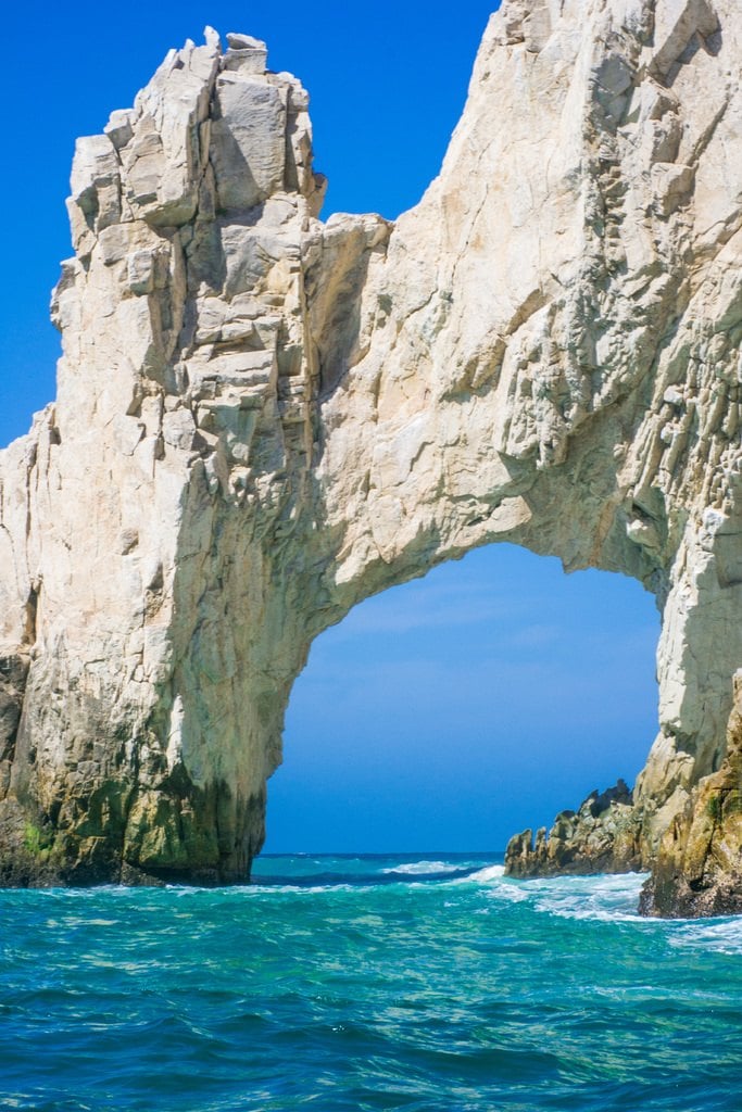 A white rock arch framing turquoise water