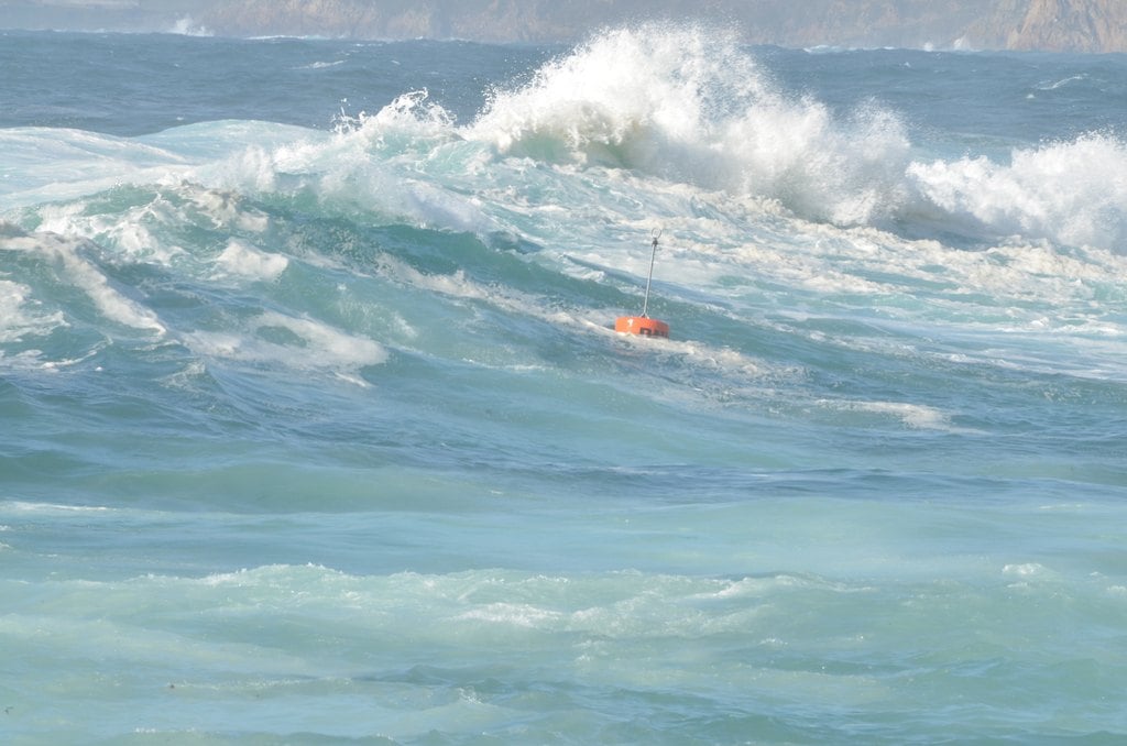 A green wave cresting with foam in open water