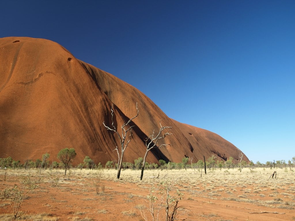 A red monolith rising above dry grassland