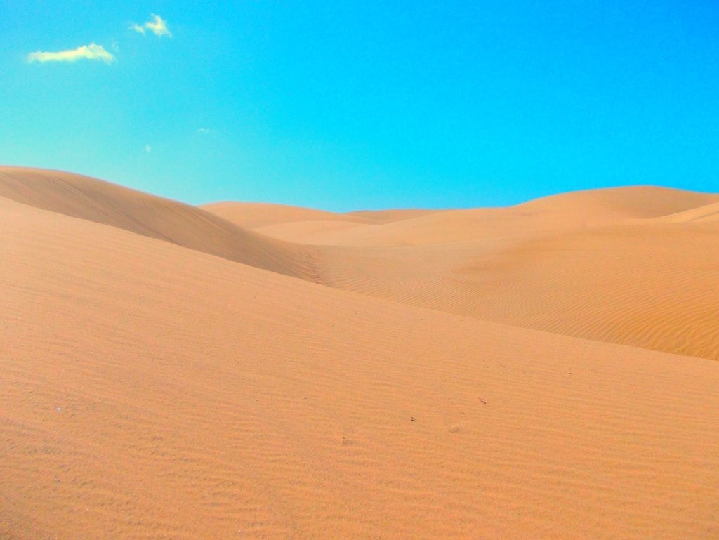 Smooth orange dunes under a saturated blue sky