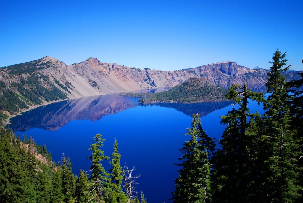 A deep blue crater lake ringed by pine trees