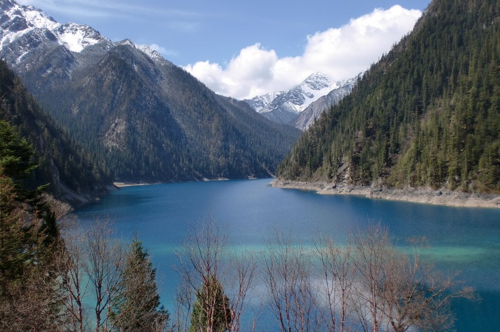 A long blue lake between steep forested slopes