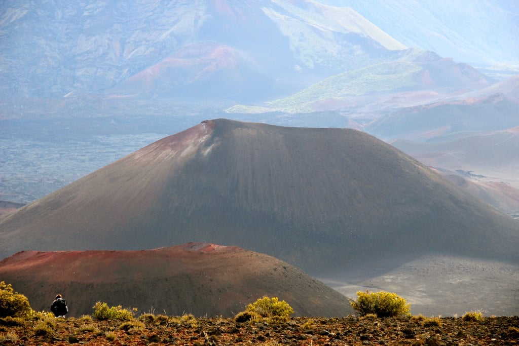 A rust-coloured volcanic cone above scrubland